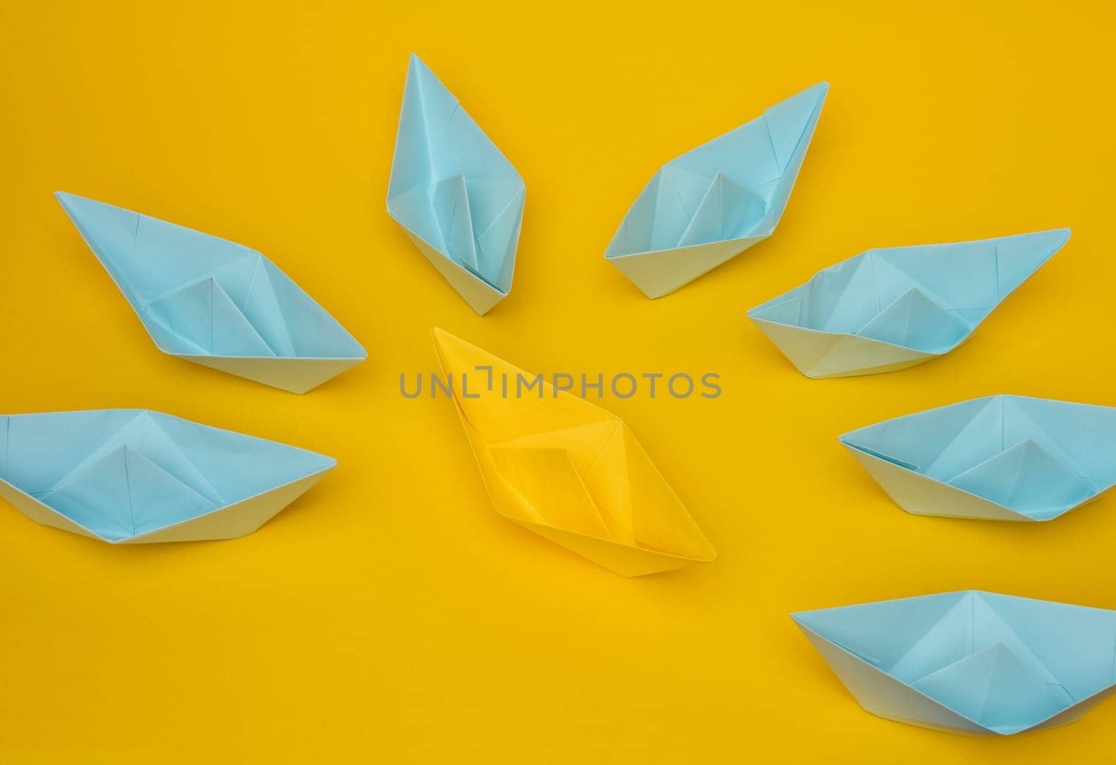 A group of blue paper boats surrounded one yellow boat, the concept of bullying, search for compromise. 