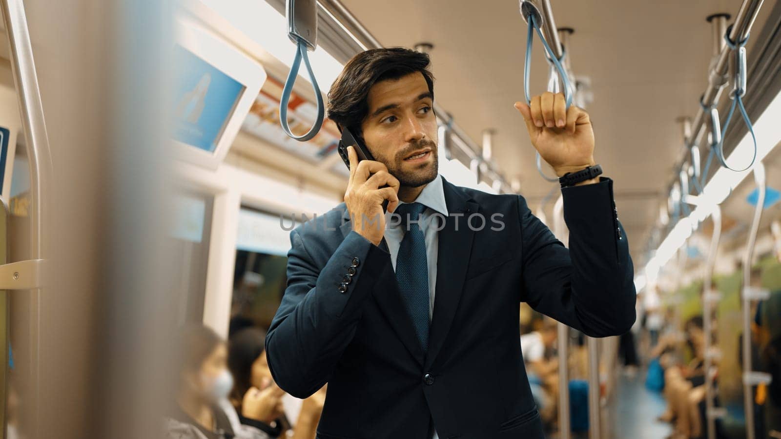 Smart business man phone calling to project manager while standing in train. Professional male leader talking to investor about marketing plan by using phone with blurring background. Exultant.