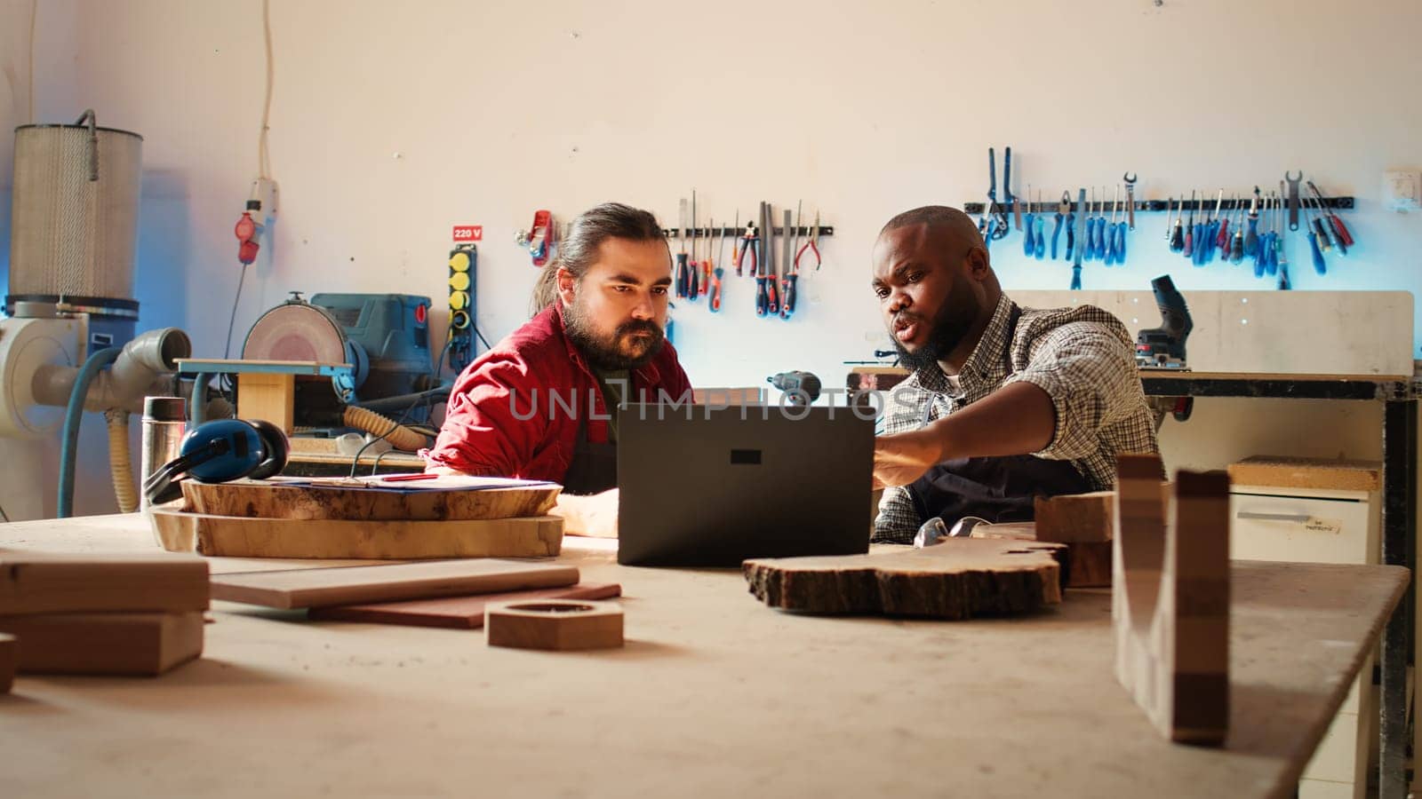 Woodworkers using laptop to design wooden objects, pointing towards screen by DCStudio