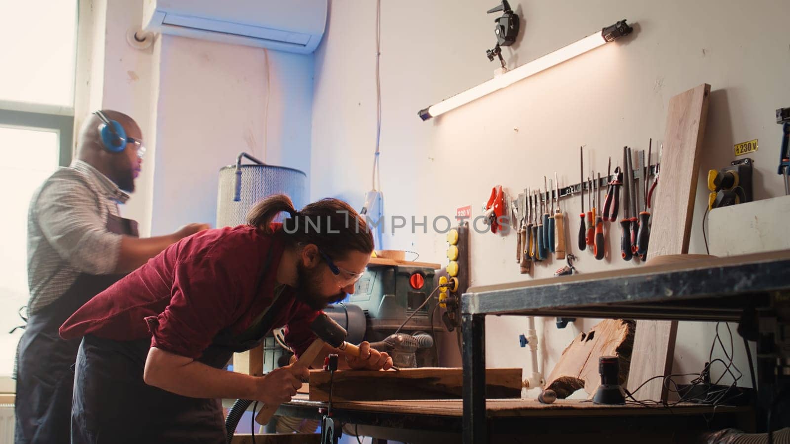 Woodworker using bench vise to hold lumber block, carving intricate designs by DCStudio