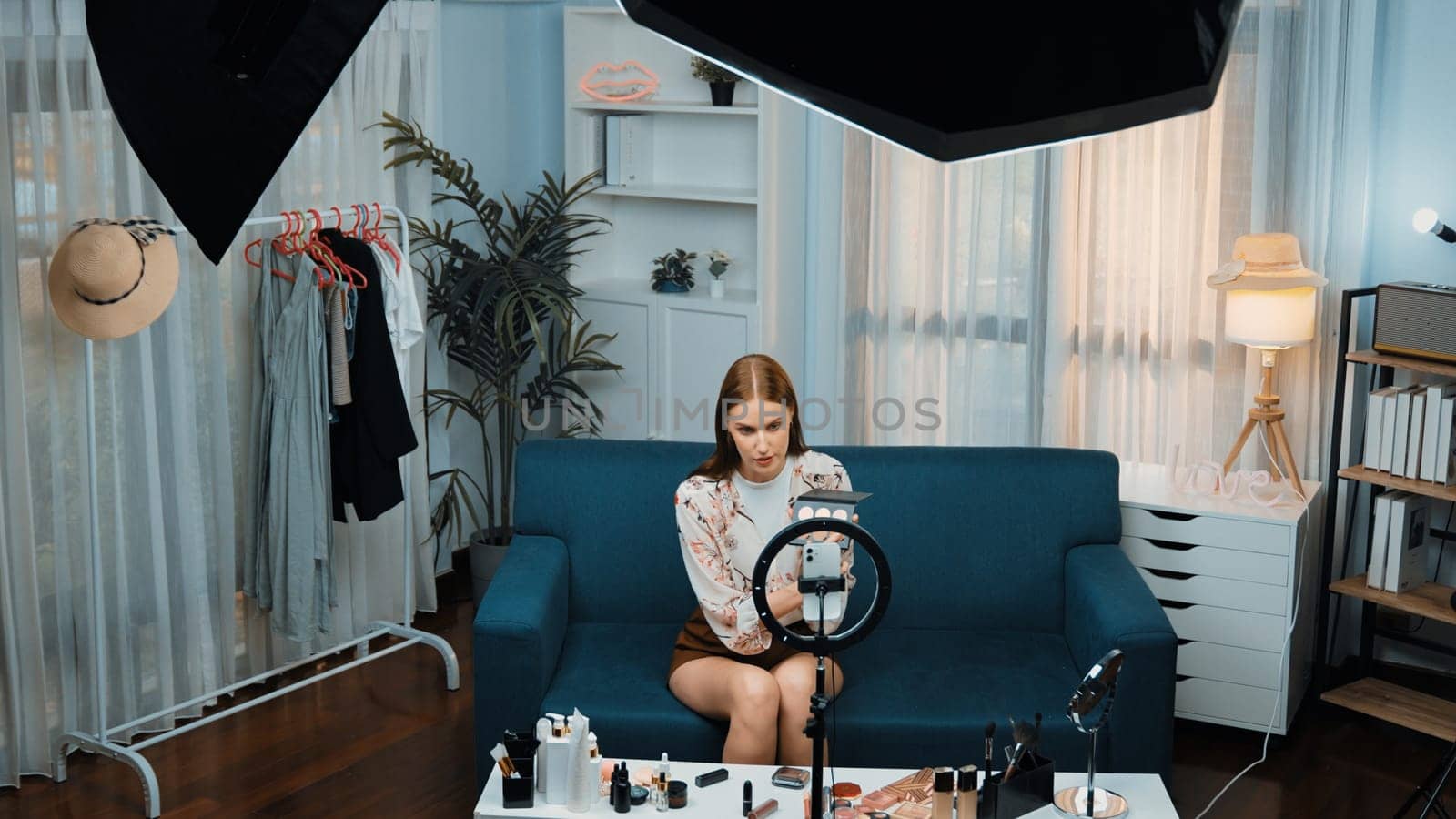 Woman influencer shoot live streaming vlog video review makeup prim social media or blog. Happy young girl with cosmetics studio lighting for marketing recording session broadcasting online.
