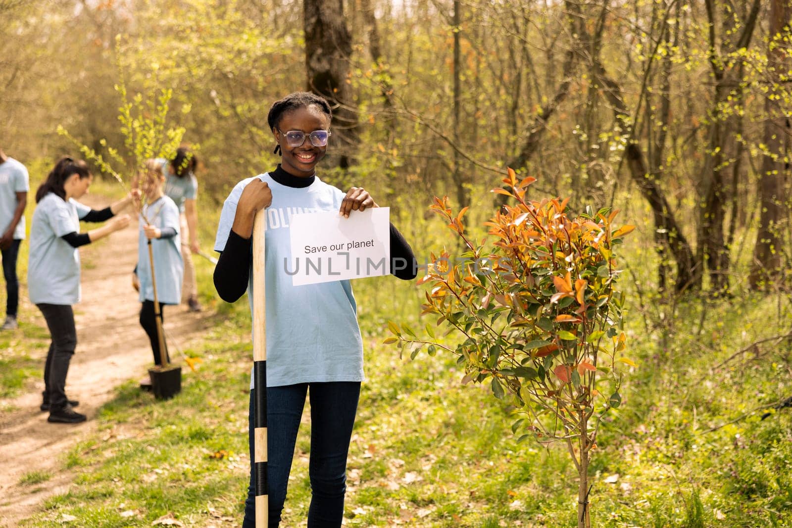 Portrait of african american girl holding banner with save our planet message, spreading ecological justice and awareness. Teenager activist posing with a poster to fight environmental pollution.