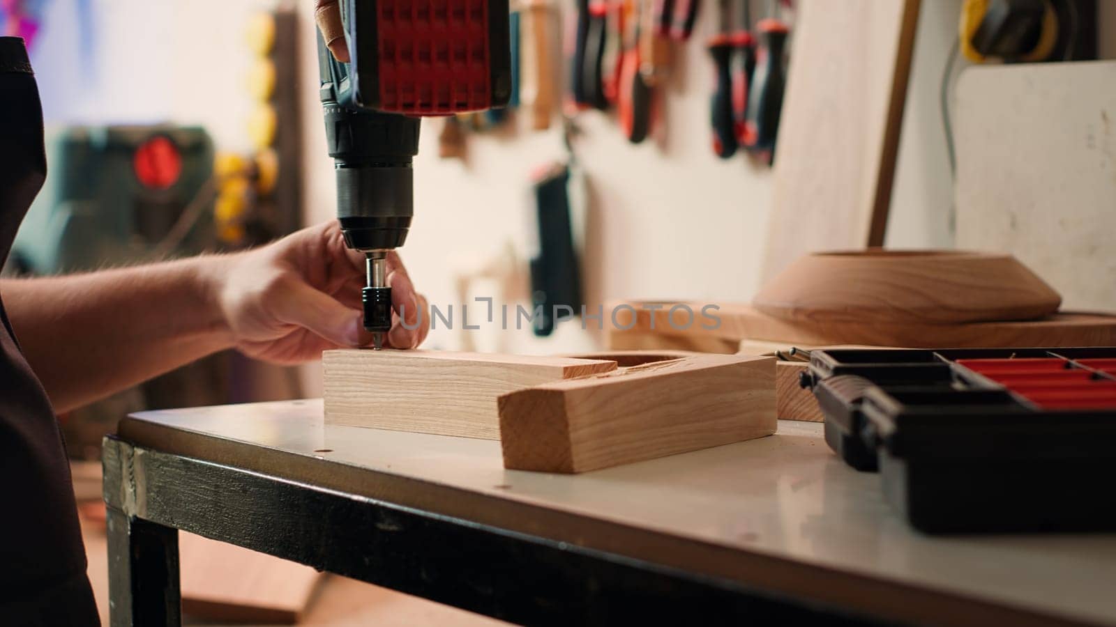 Manufacturer in assembly shop picking screw from tool box by DCStudio