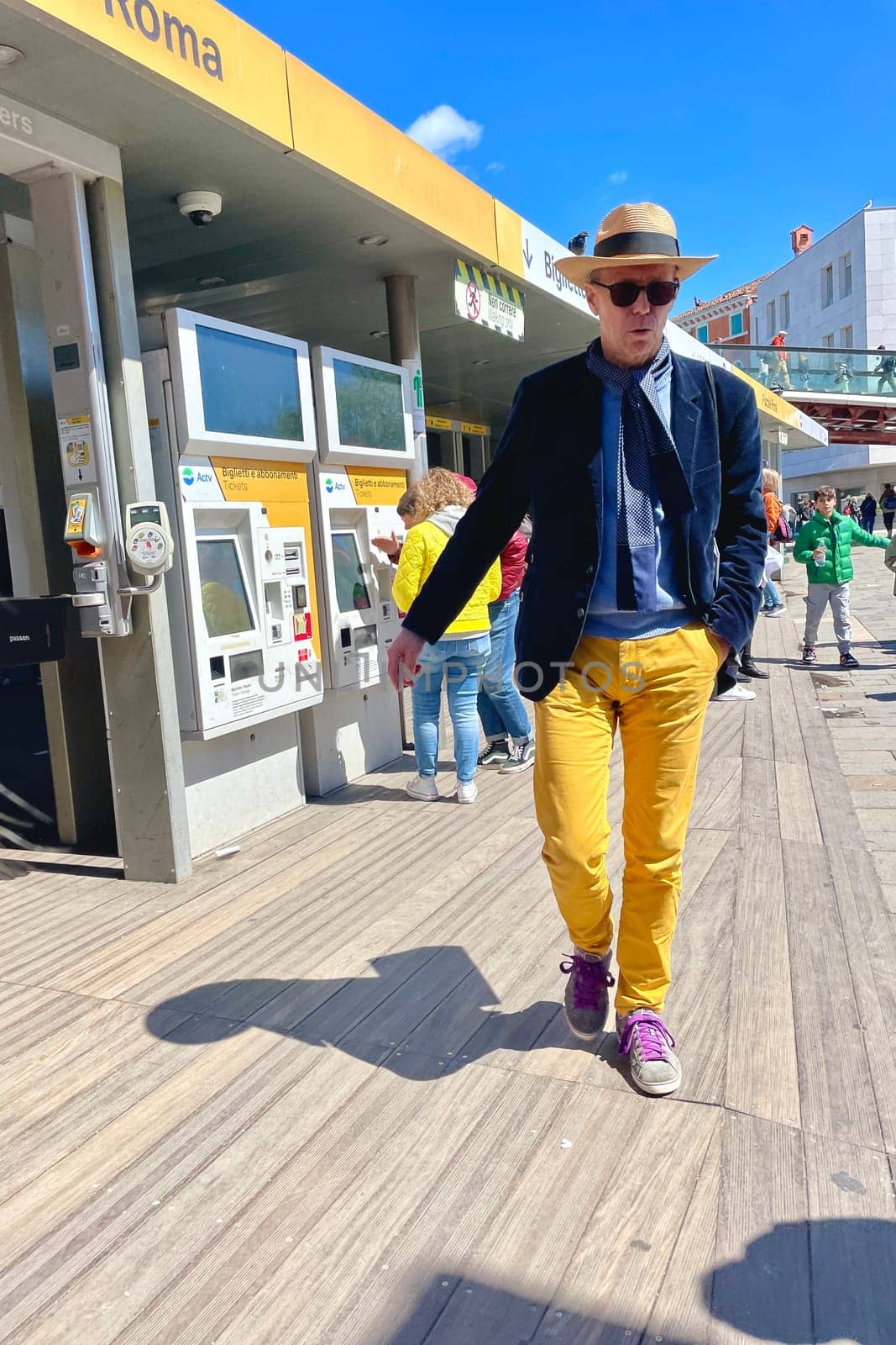 Italy, Venice, April 25, 2024, spring. A tall Italian man in yellow pants, a hat, a blue jacket by MilaLazo
