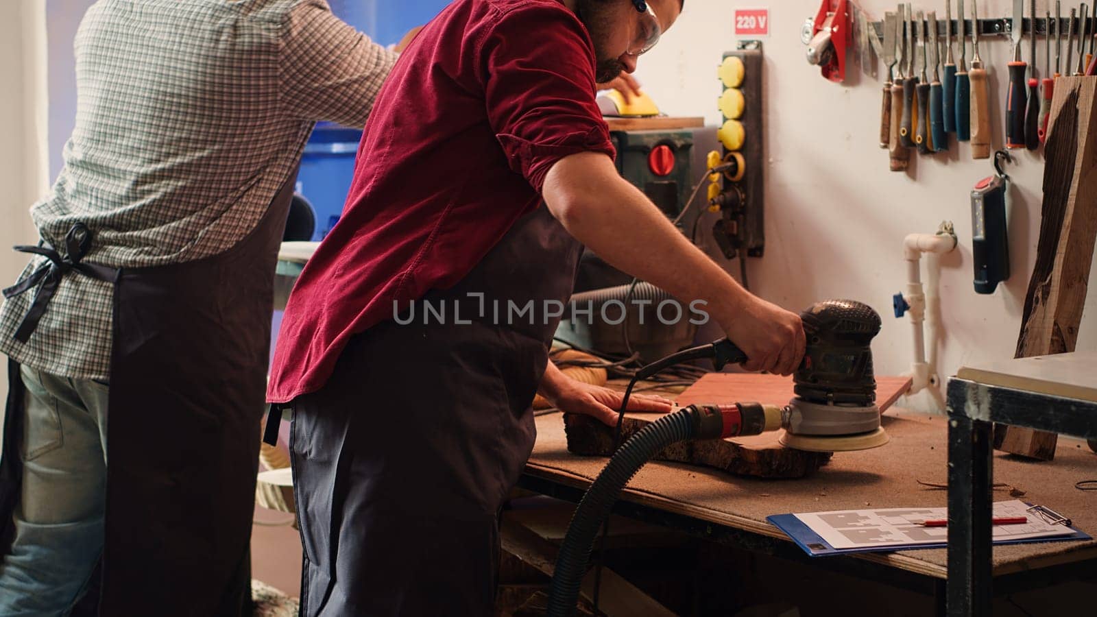 Craftsperson uses angle grinder on wood after checking schematics by DCStudio