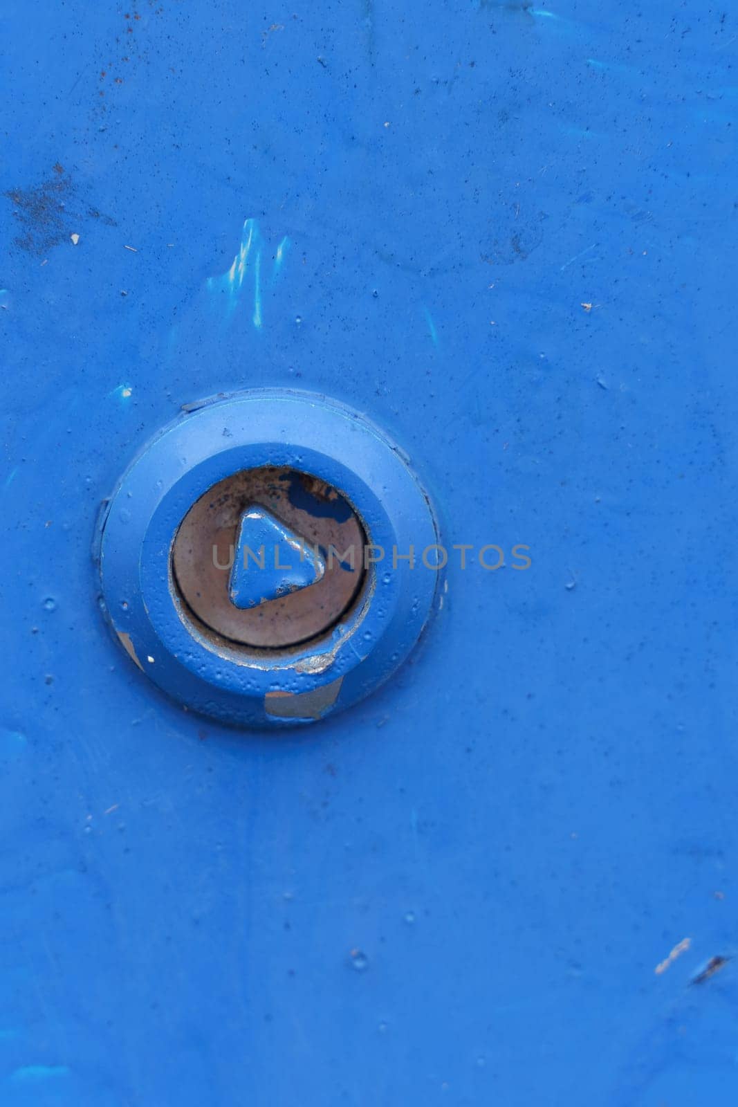 A detailed view showing a rusty bolt embedded in a textured blue metal surface, highlighting the contrast between the worn metal elements and the vibrant blue paint.
