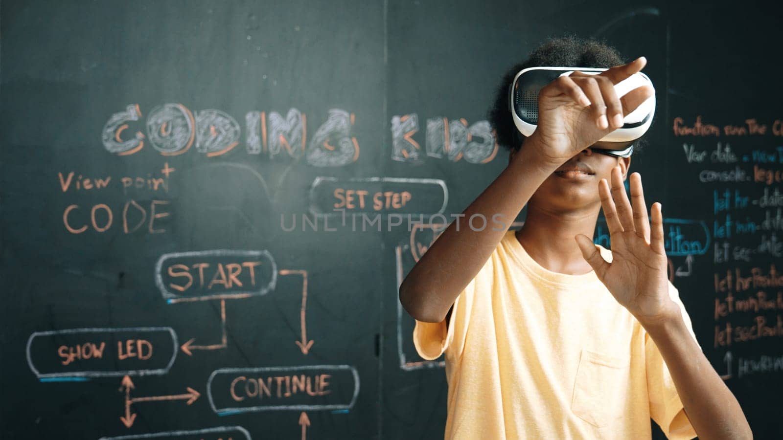 African student use VR headset learning innovation at metaverse while standing at blackboard with coding or programing prompt written at STEM technology classroom. Creative innovation. Edification.