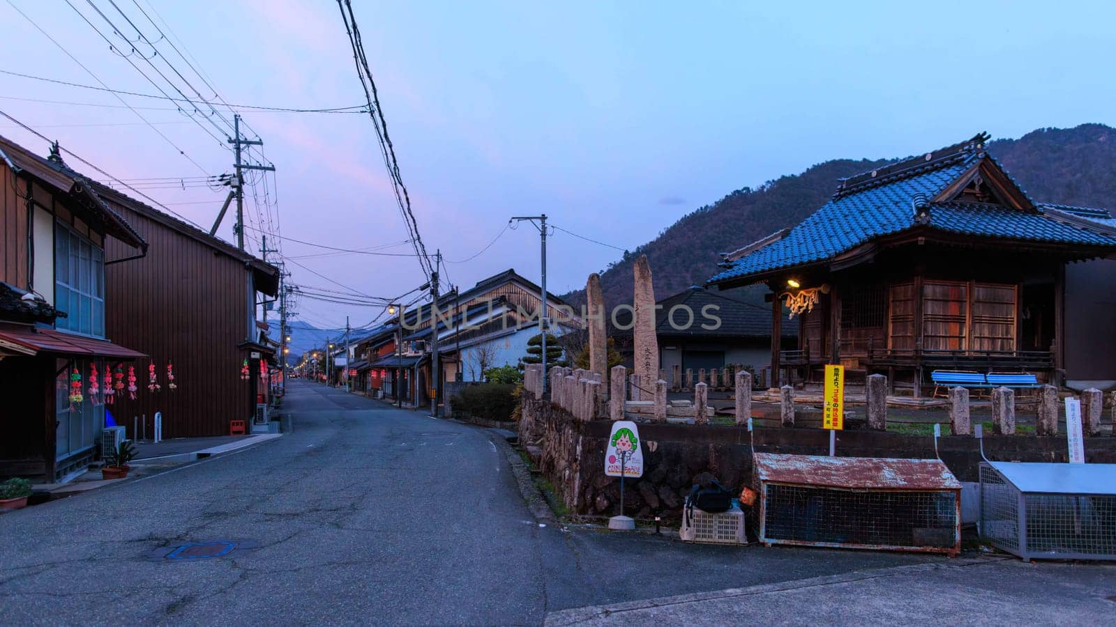 Quiet street with traditional wooden houses in Japanese village at sunset by Osaze