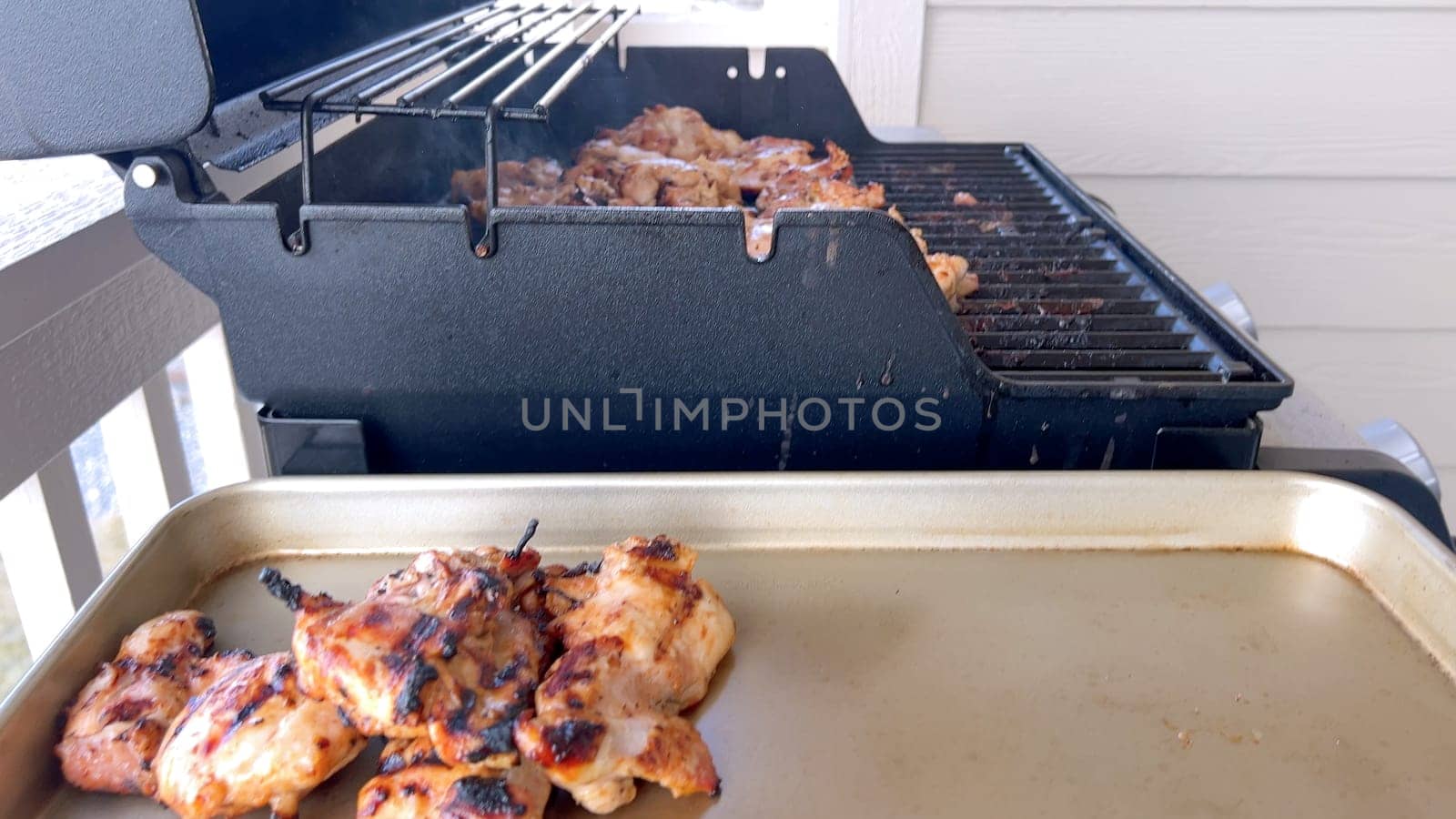 A close-up image capturing the process of grilling marinated chicken pieces, with a person expertly flipping them to ensure even cooking on a classic outdoor barbecue grill.