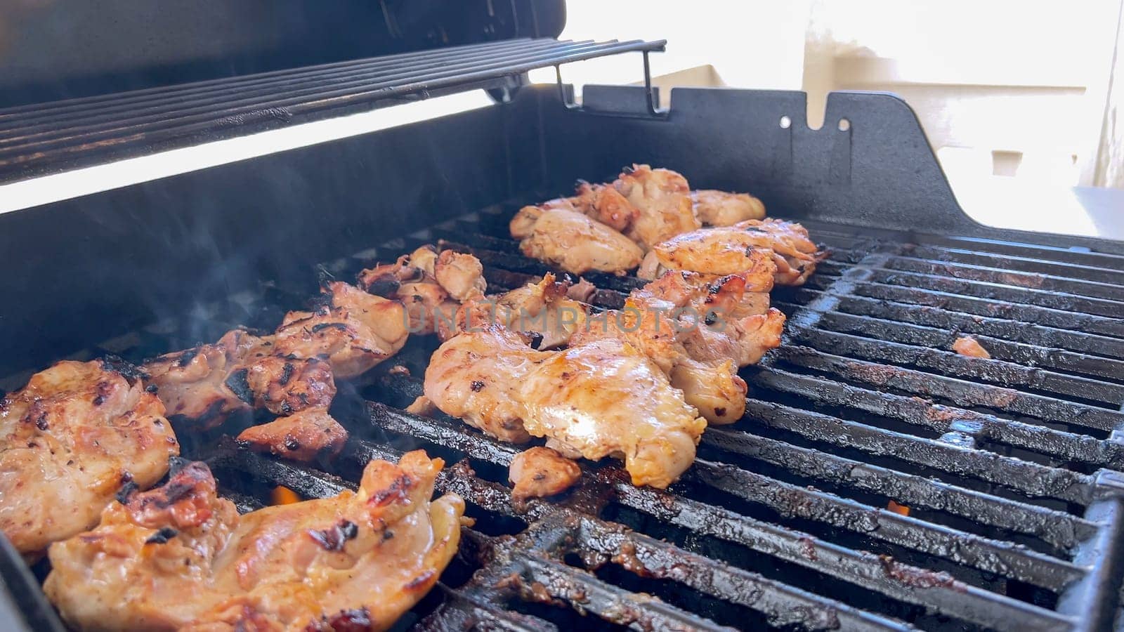 A close-up image capturing the process of grilling marinated chicken pieces, with a person expertly flipping them to ensure even cooking on a classic outdoor barbecue grill.