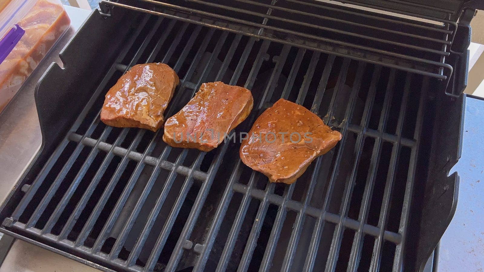 Juicy Steaks Sizzling on an Outdoor Barbecue Grill by arinahabich