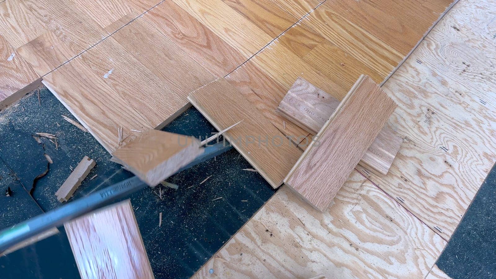 A scattered array of hardwood planks lies on a partially completed floor, highlighting the ongoing work of a home renovation project focused on installing new wood flooring.