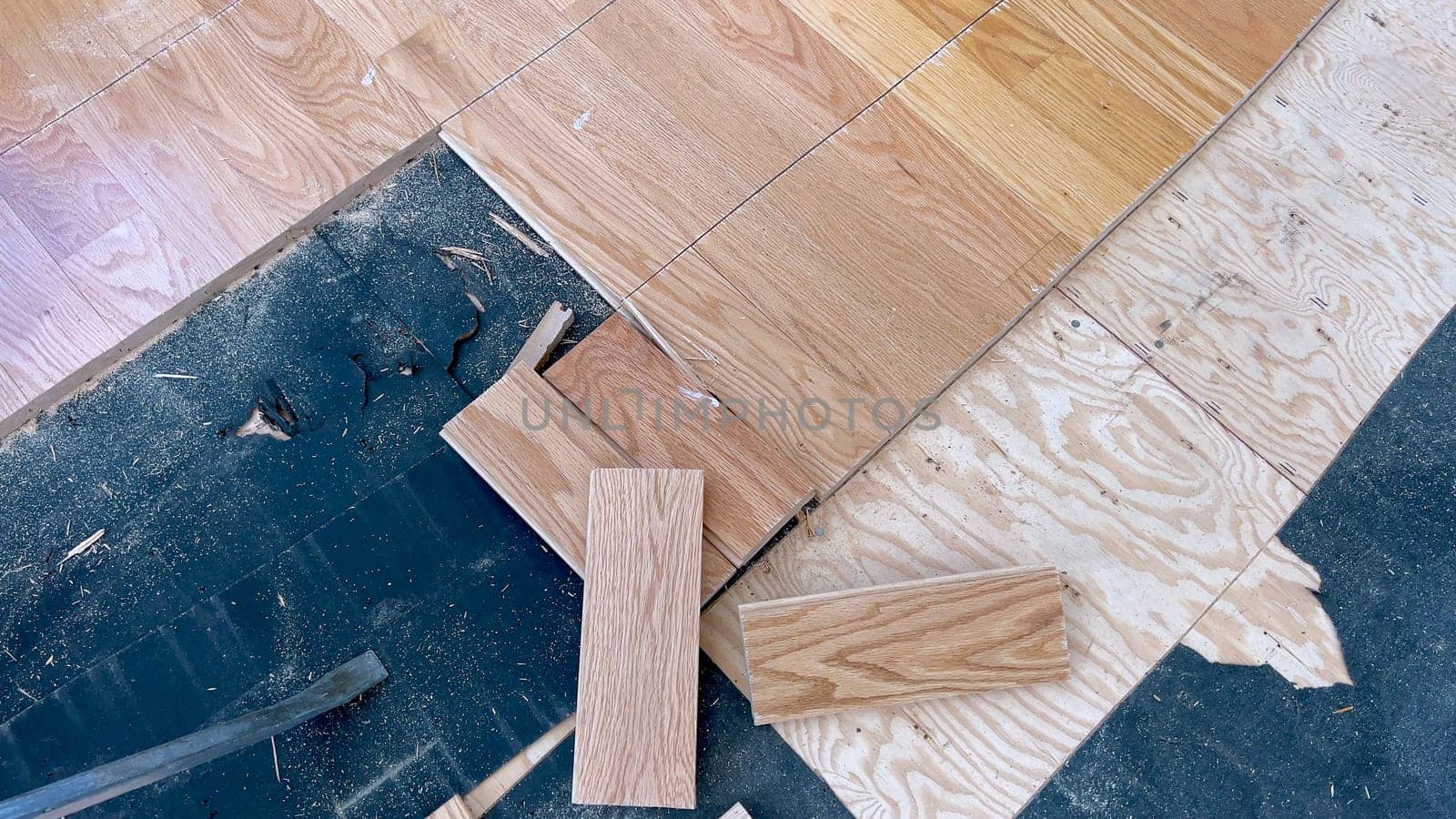 A scattered array of hardwood planks lies on a partially completed floor, highlighting the ongoing work of a home renovation project focused on installing new wood flooring.