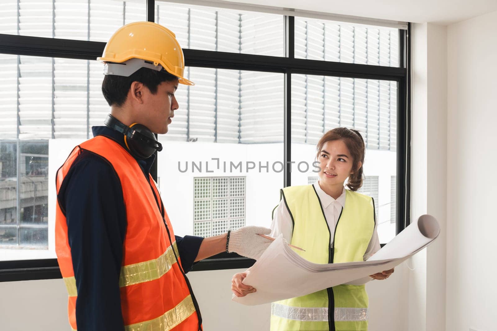 The female foreman discusses with the engineering team about the construction project plans and plans. by wichayada