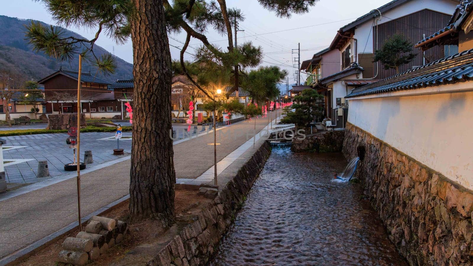 Flowing water in canal by historic street in Takeda Town, Japan at dusk. High quality photo