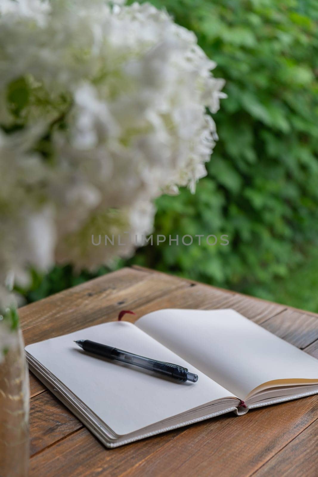 Empty white open paper notebook in wooden table outdoors in garden. Concept of self reflection discovery journal, writing gratitude journal