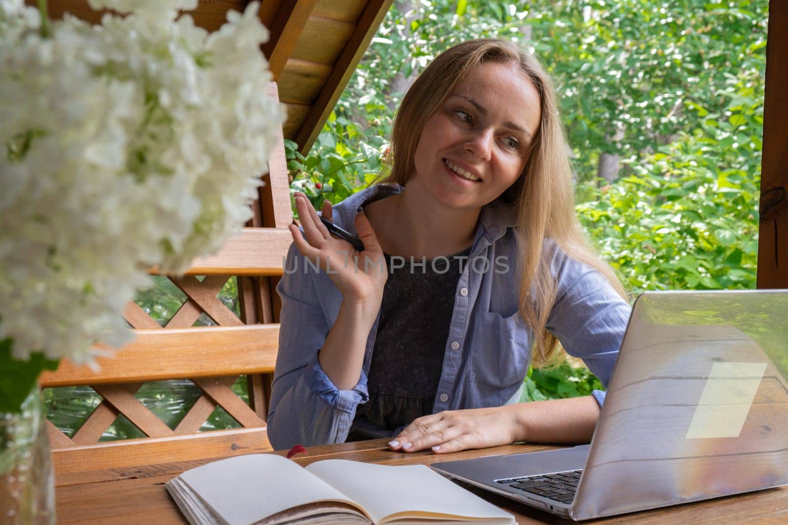 Young woman freelancer working online using laptop and enjoying the beautiful nature outdoors in garden. Online meeting education. Worcation, hybrid work model by anna_stasiia