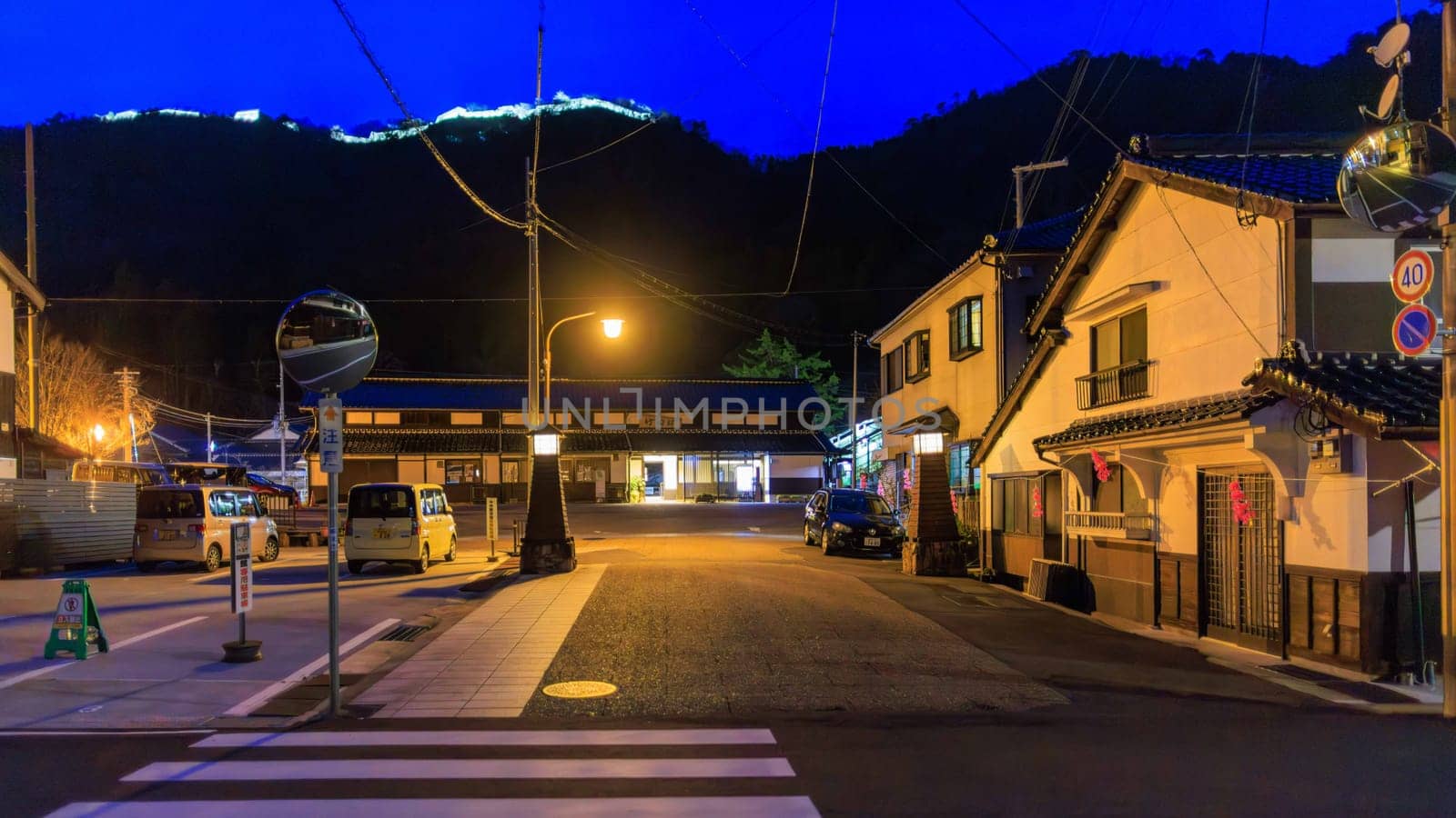 Takeda, Japan - March 28, 2023: Empty road in front of train station with castle lights on hill above. High quality photo