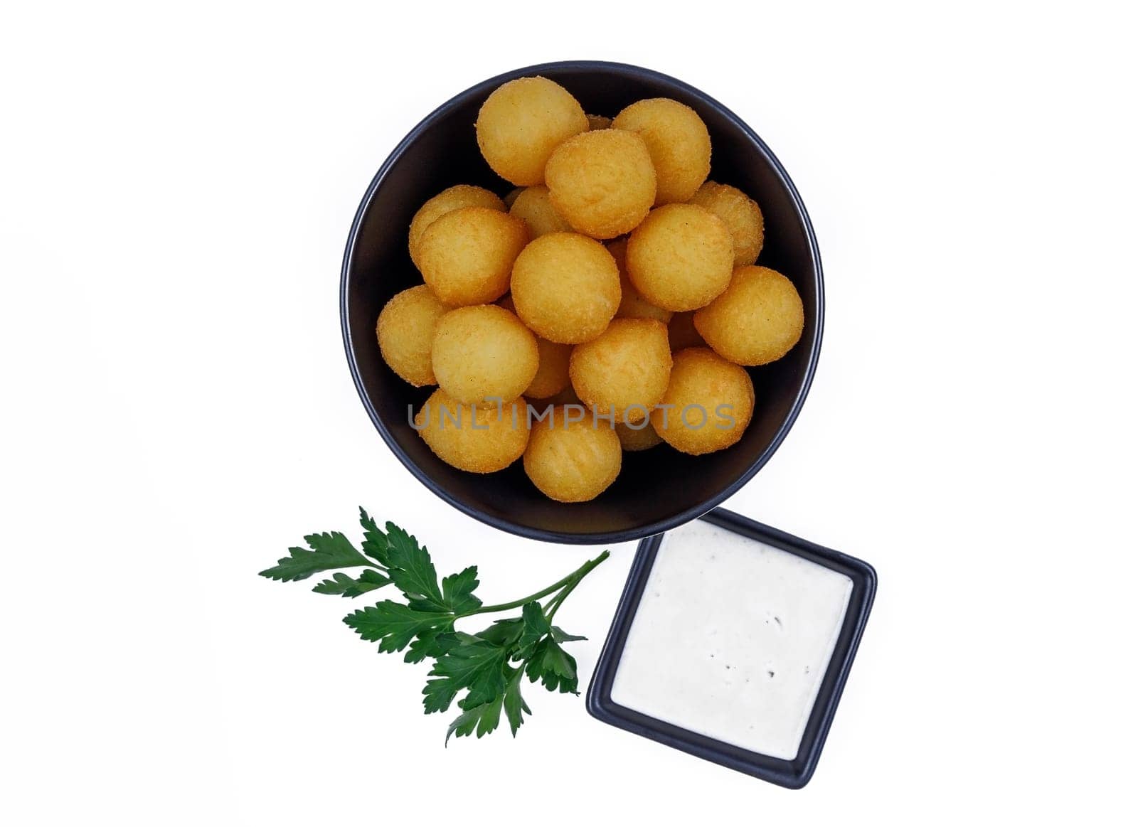 Potato balls in a black plate with sauce and herbs isolated on white background. by Mixa74