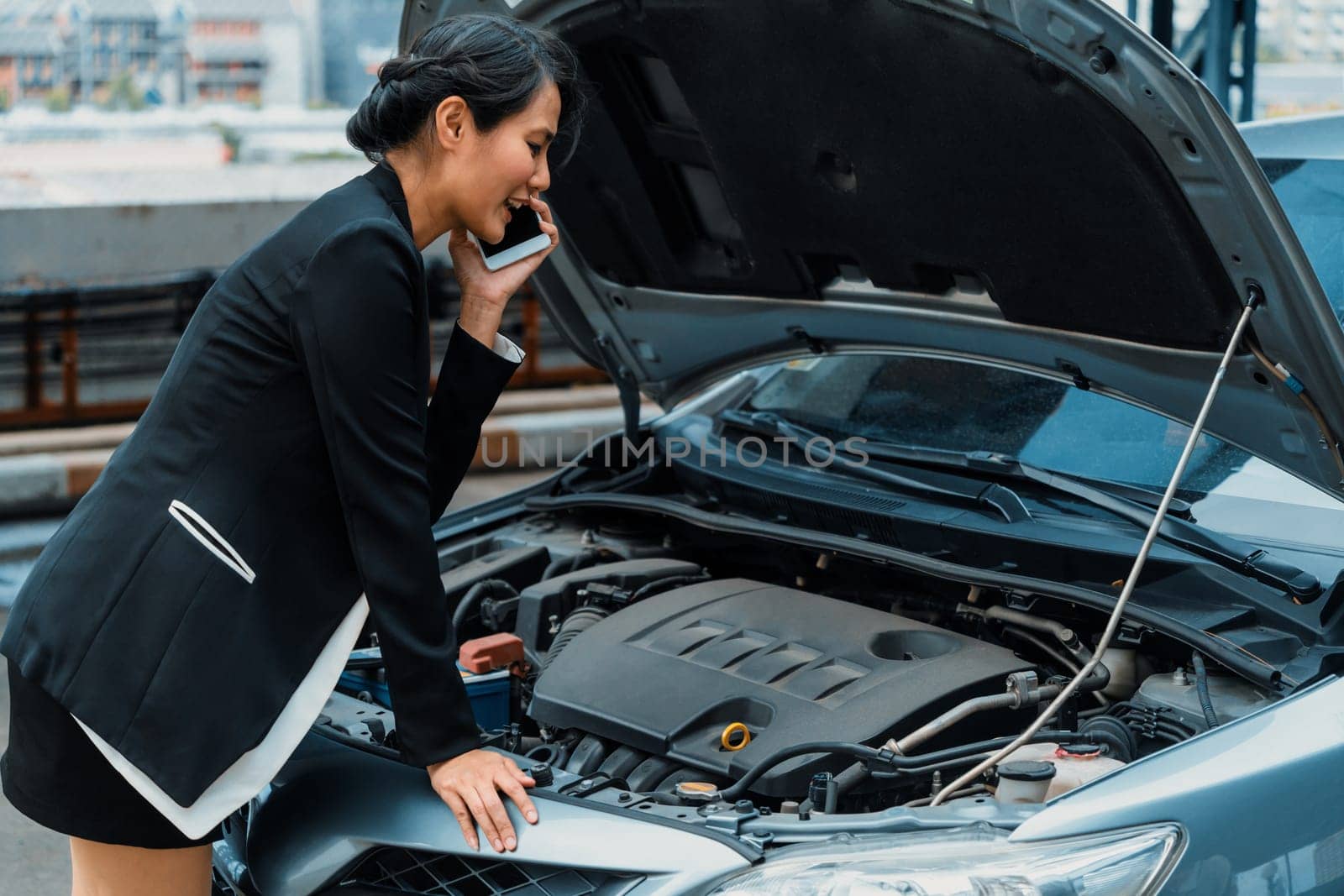 Young businesswoman whose car breakdown uses mobile phone to call for roadside assistance service. Travel and transportation vehicle problem. uds