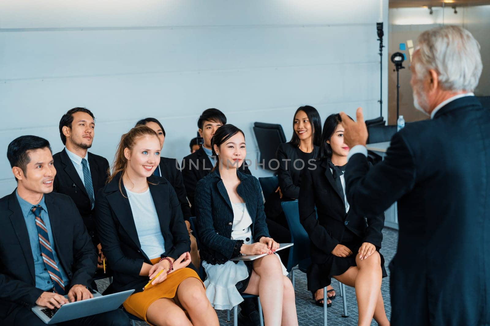 Senior leader speaker speaks to public people audience in training workshop or conference. Mature lecturer is CEO executive manager leading symposium event. International business seminar concept. uds