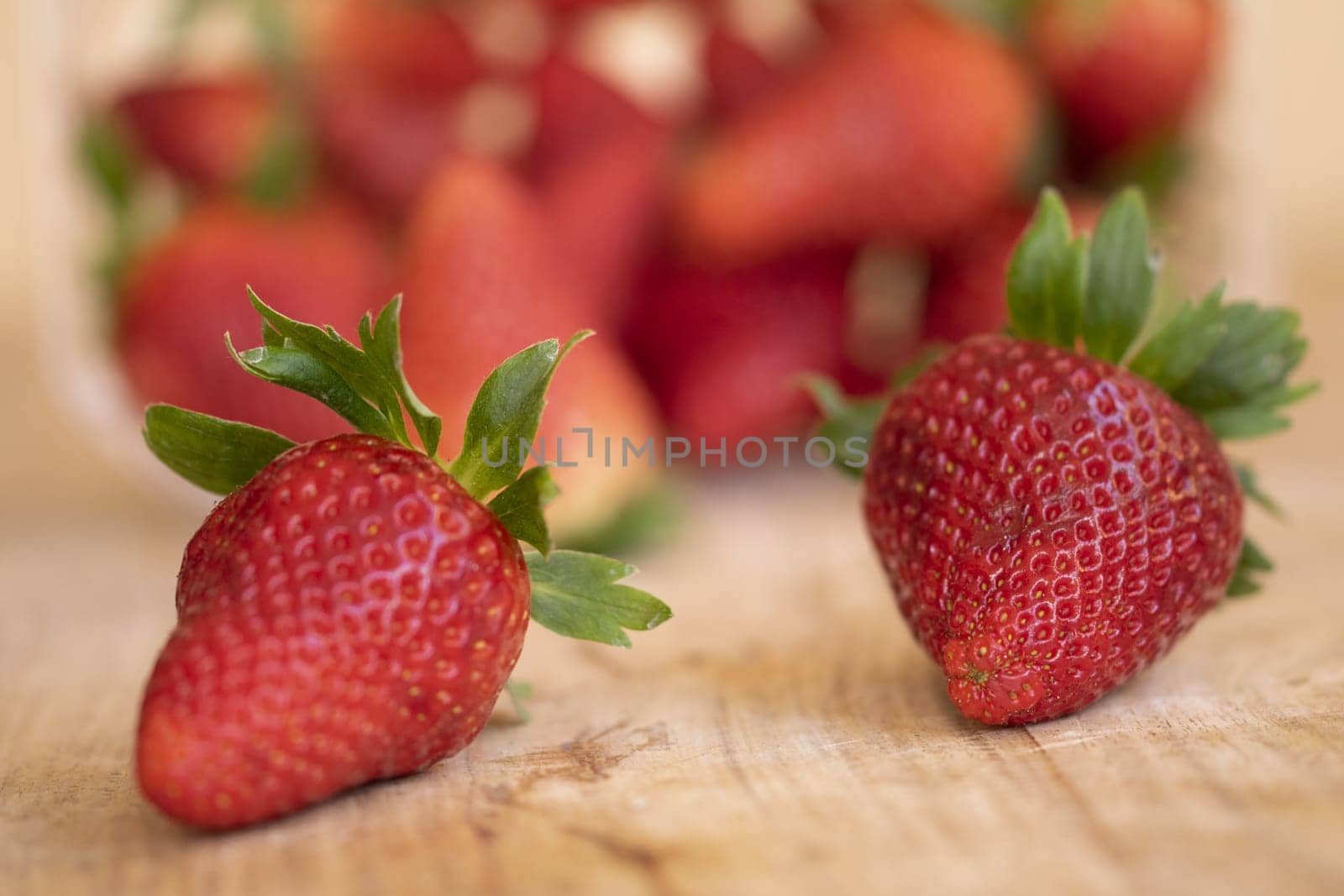 two fresh and ripe strawberries on a wooden table