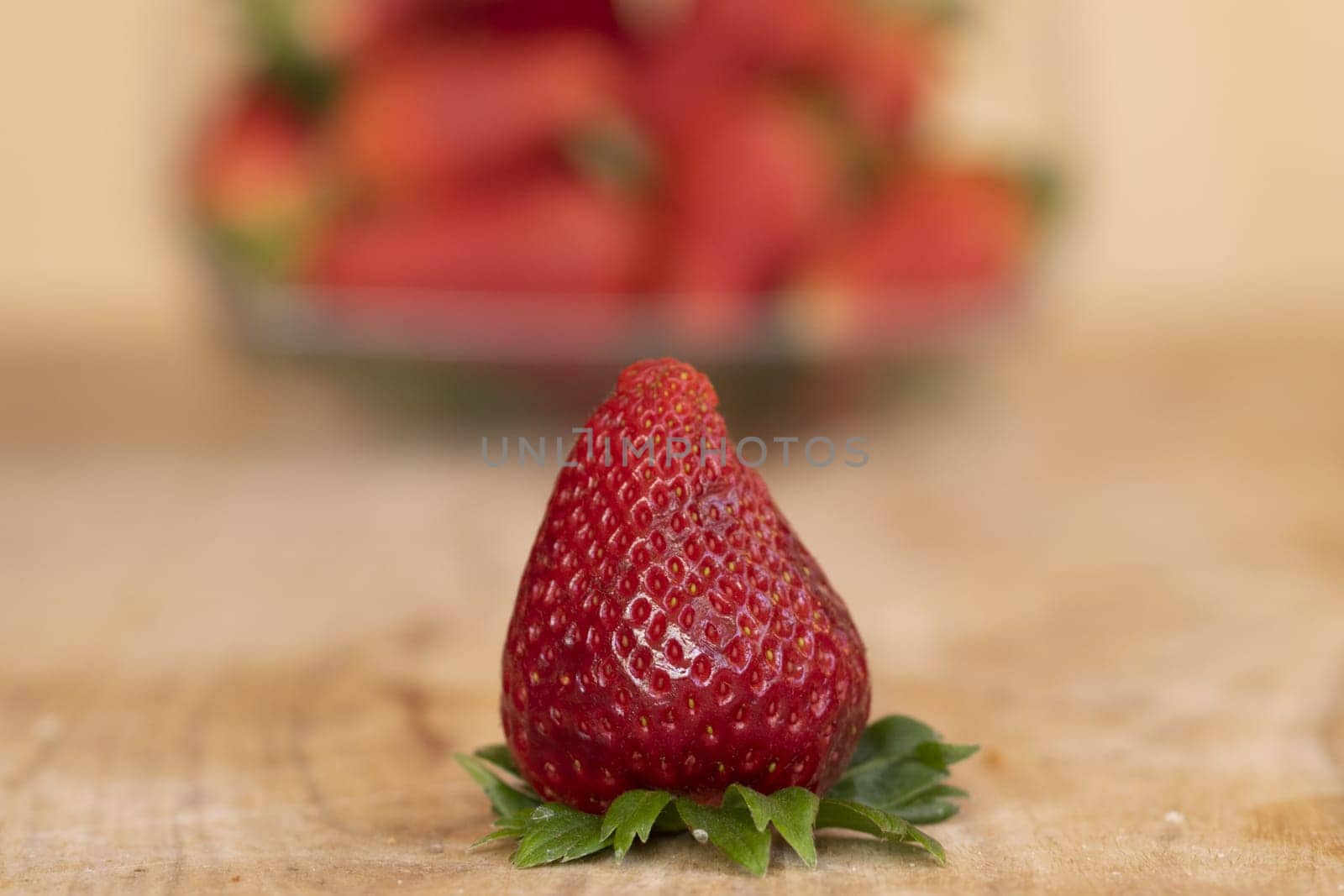 ripe strawberry in front of a basket of other strawberries
