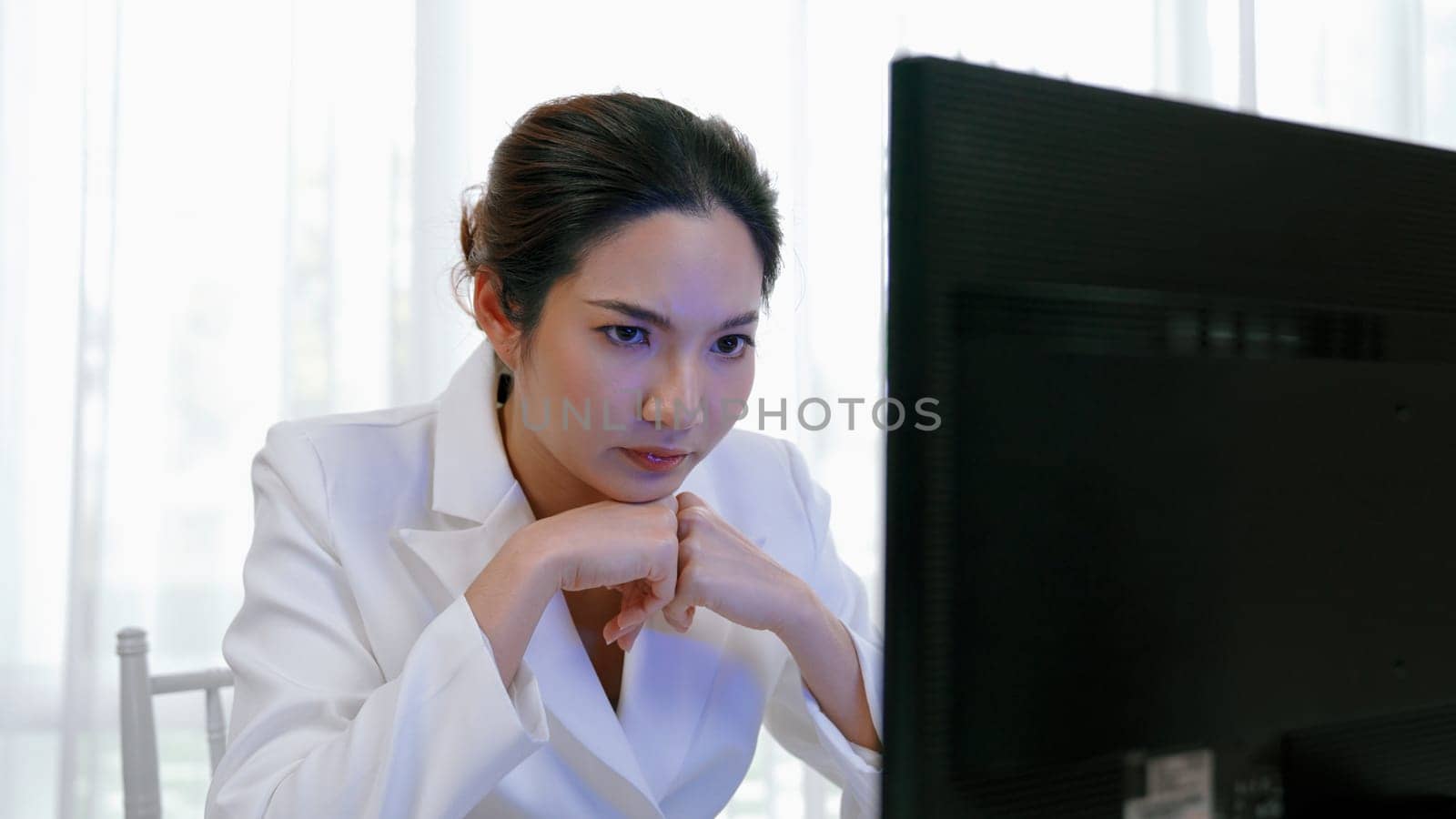 Diligent and serious working young businesswoman sitting on the workspace desk using laptop computer for internet online content writing or secretary remote working from home. Vivancy