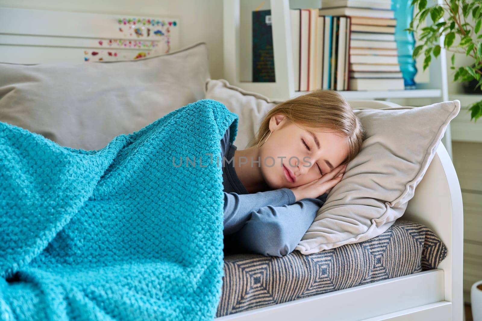 Sleeping relaxed resting young teenage female, with her eyes closed, lying on pillow under blanket at home on couch. Health, rest calm peace, beauty, lifestyle, youth concept