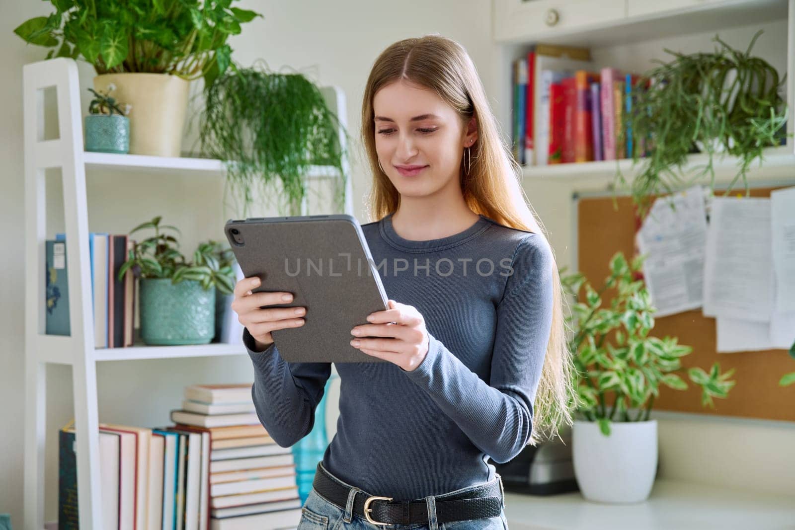 Young teenage female using digital tablet, home interior. by VH-studio