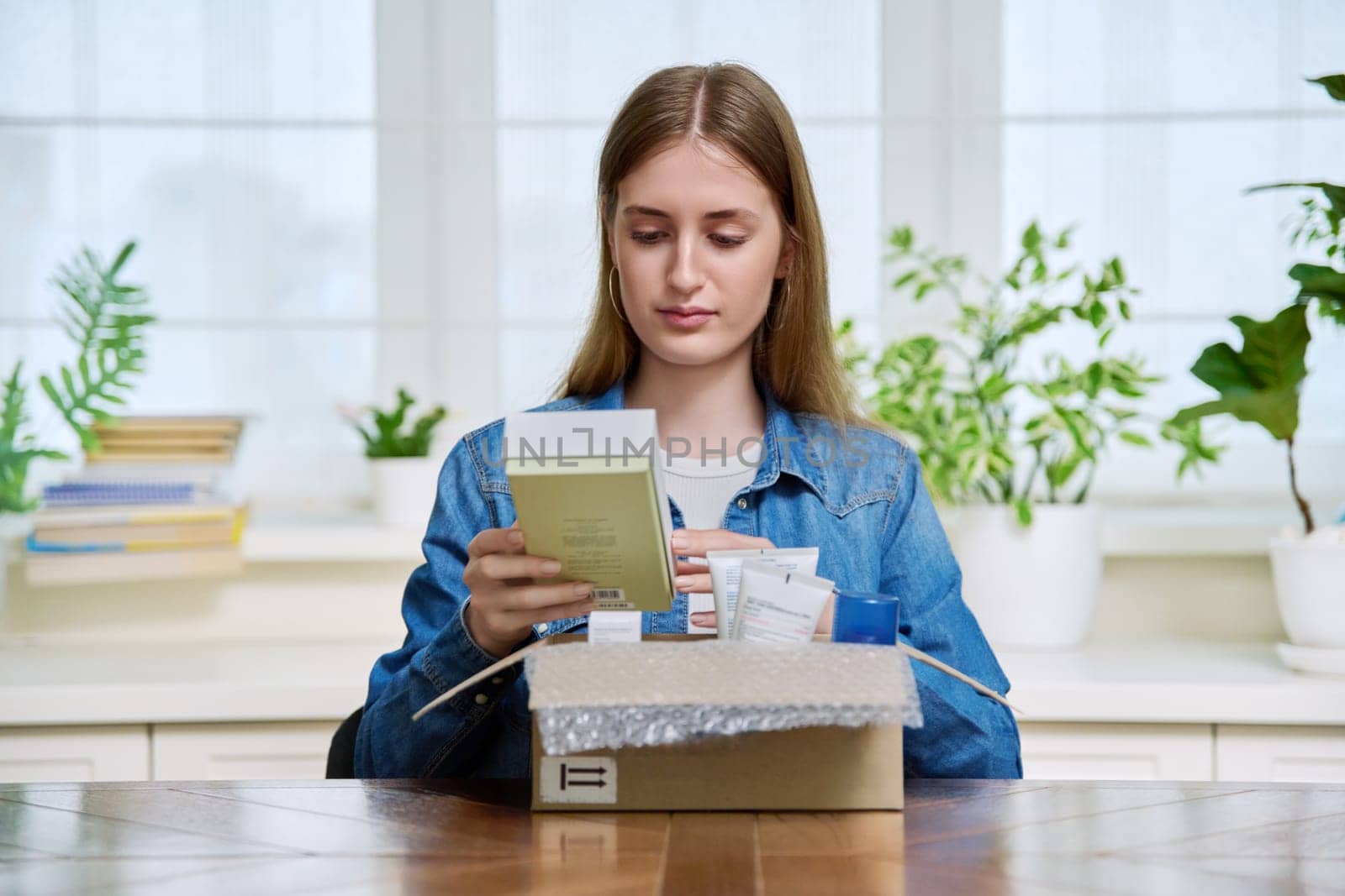 Young female customer sitting at home unpacking cardboard box with online purchases by VH-studio