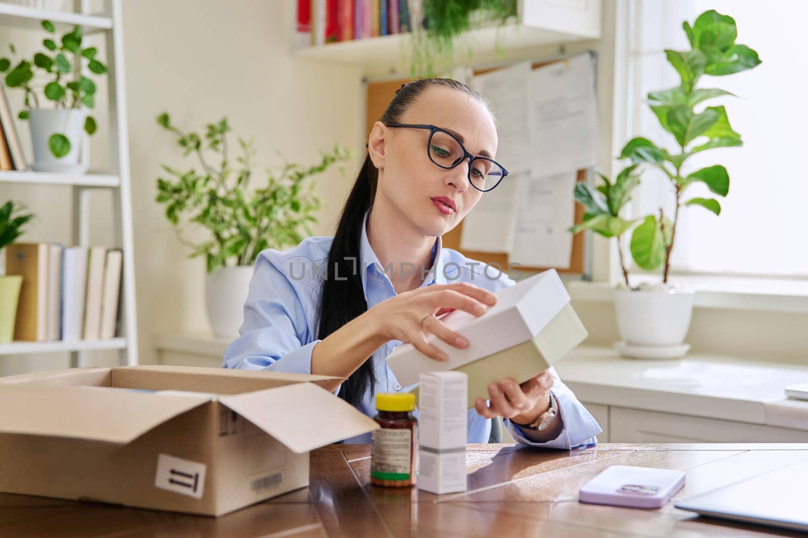 Female customer sitting at home unpacking cardboard box with online purchases by VH-studio