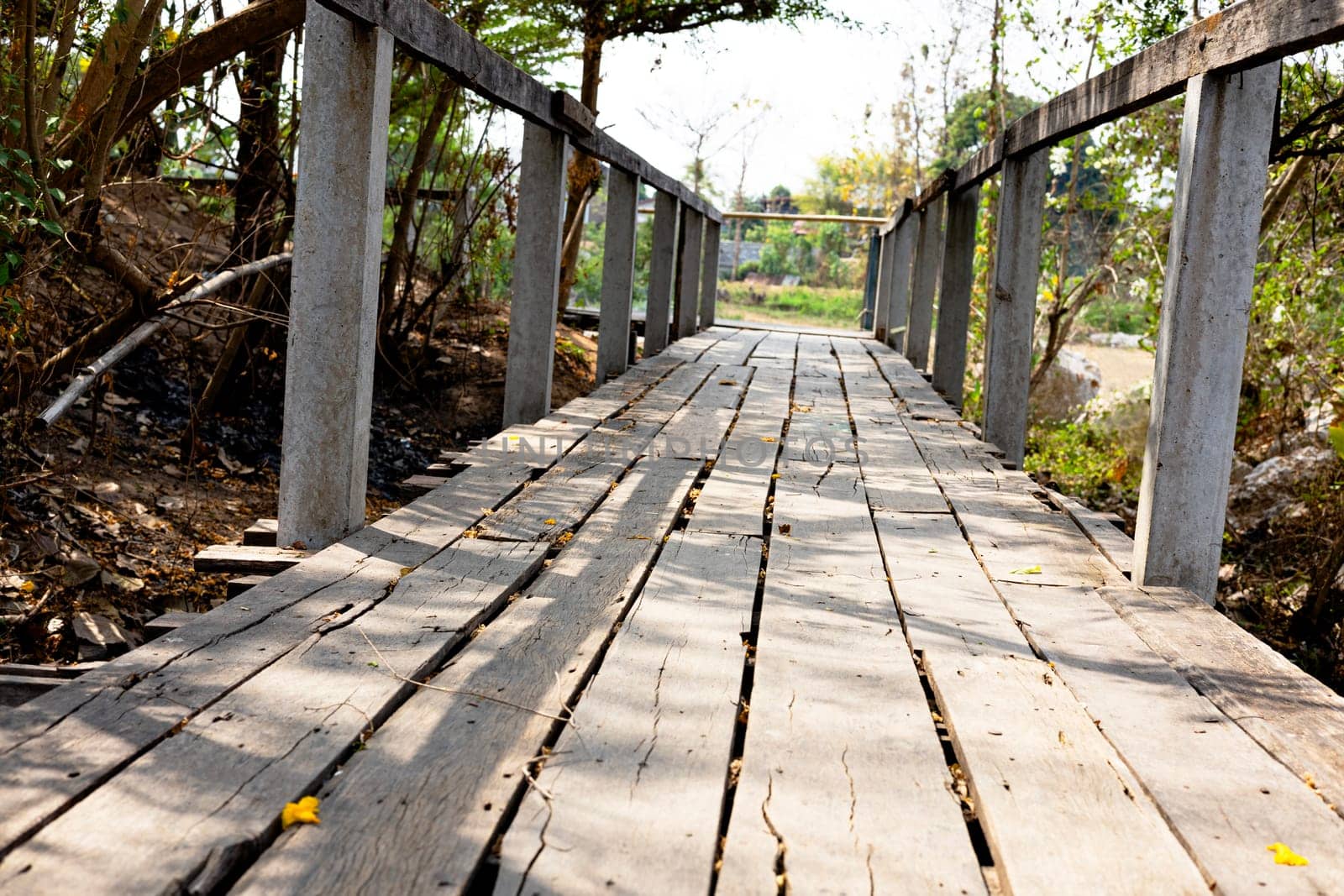 Wood bridge going over a river in a city park. Deserted Wooden Boardwalk Leading Away Through.