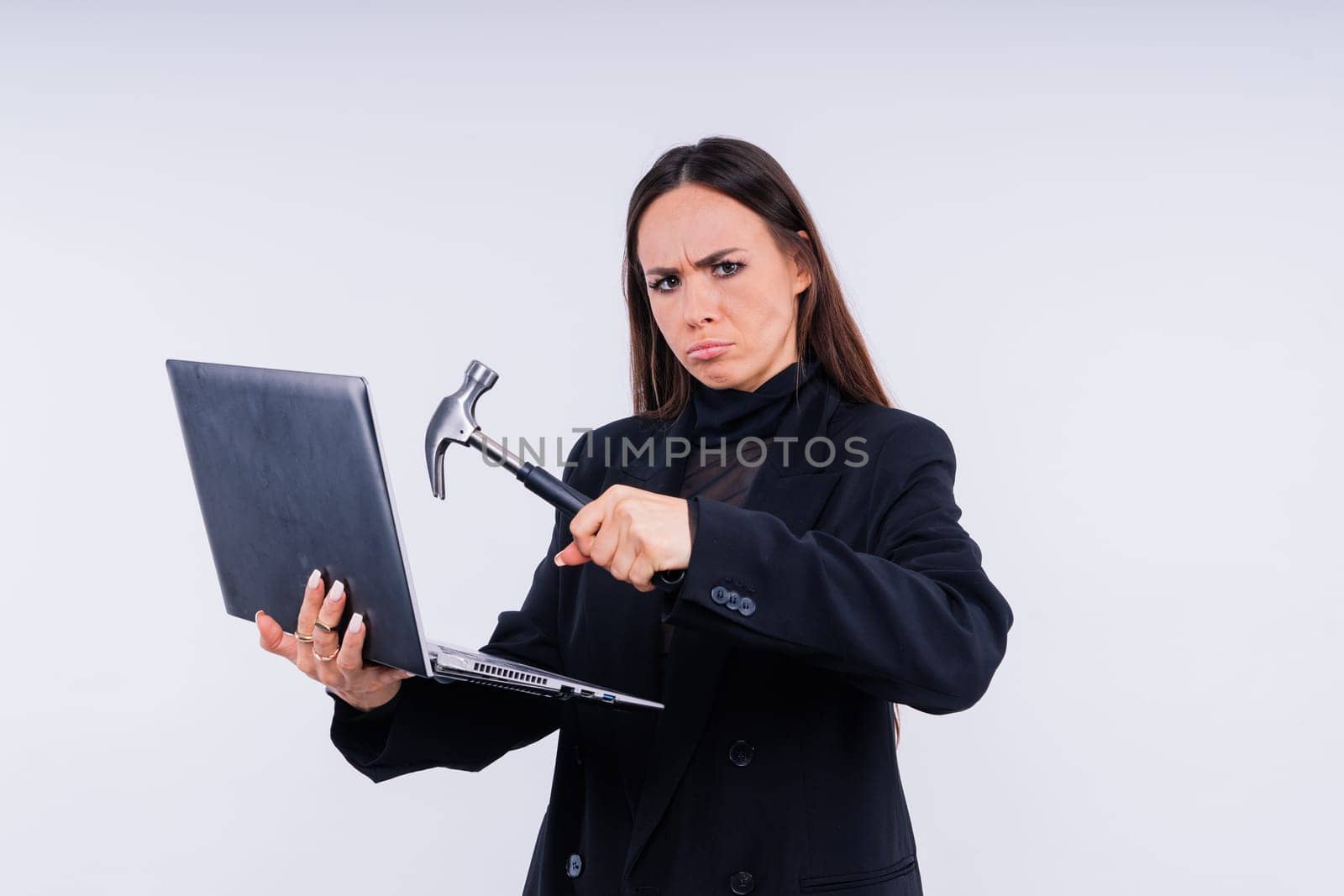 Attractive woman wearing business suit with computer angry facial expression holding a hammer by Zelenin