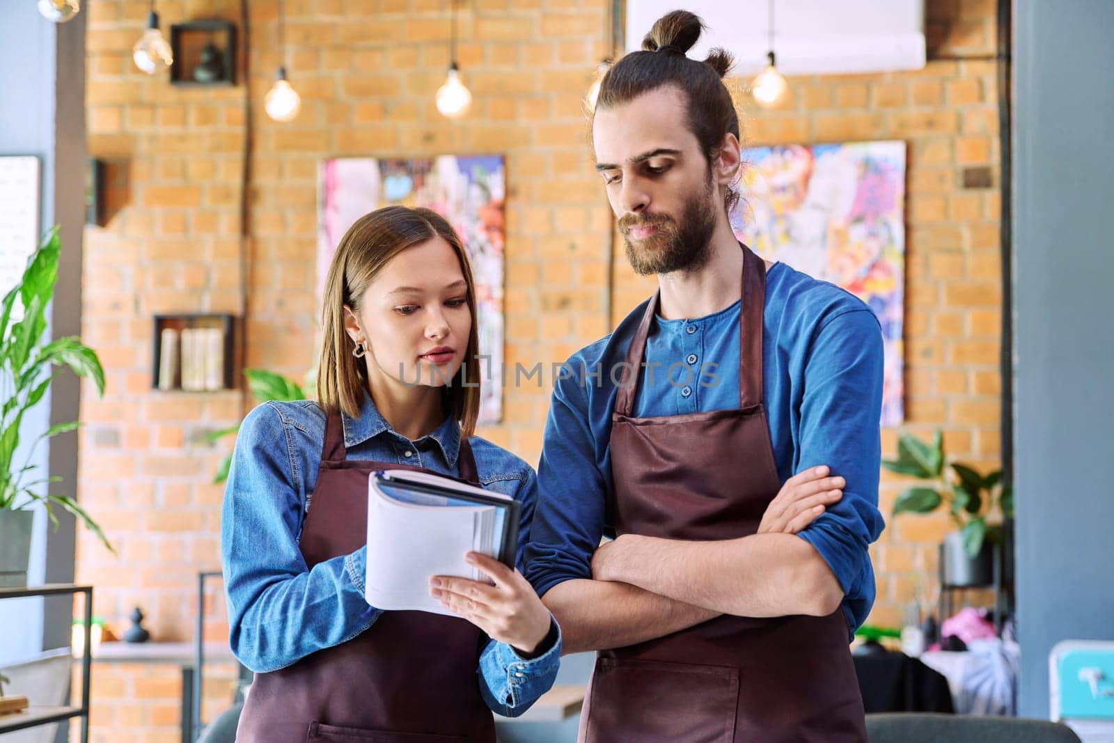 Business team, confident colleagues young man and woman in aprons with notebook by VH-studio