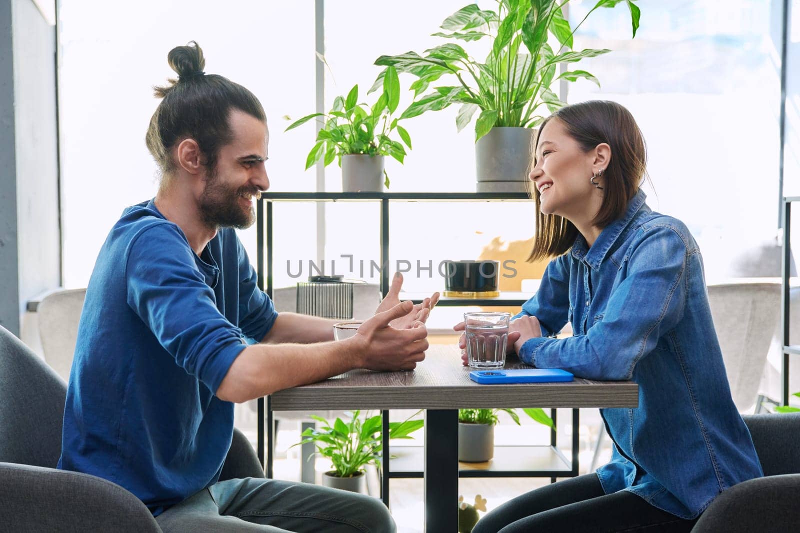 Laughing cheerful young couple sitting together in cafe by VH-studio