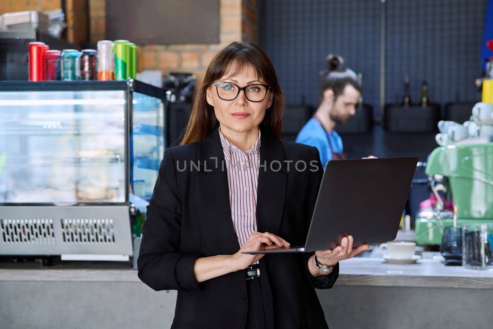 Portrait of confident business woman accountant financier lawyer small business owner. Successful middle-aged female using laptop computer looking at camera background coffee shop cafeteria restaurant