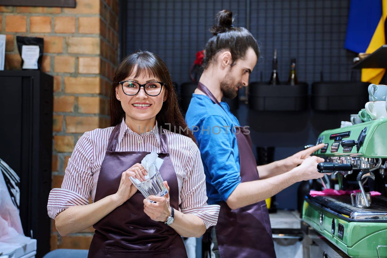 Teamwork, man and woman in aprons working together at bar counter in coffee shop cafe by VH-studio