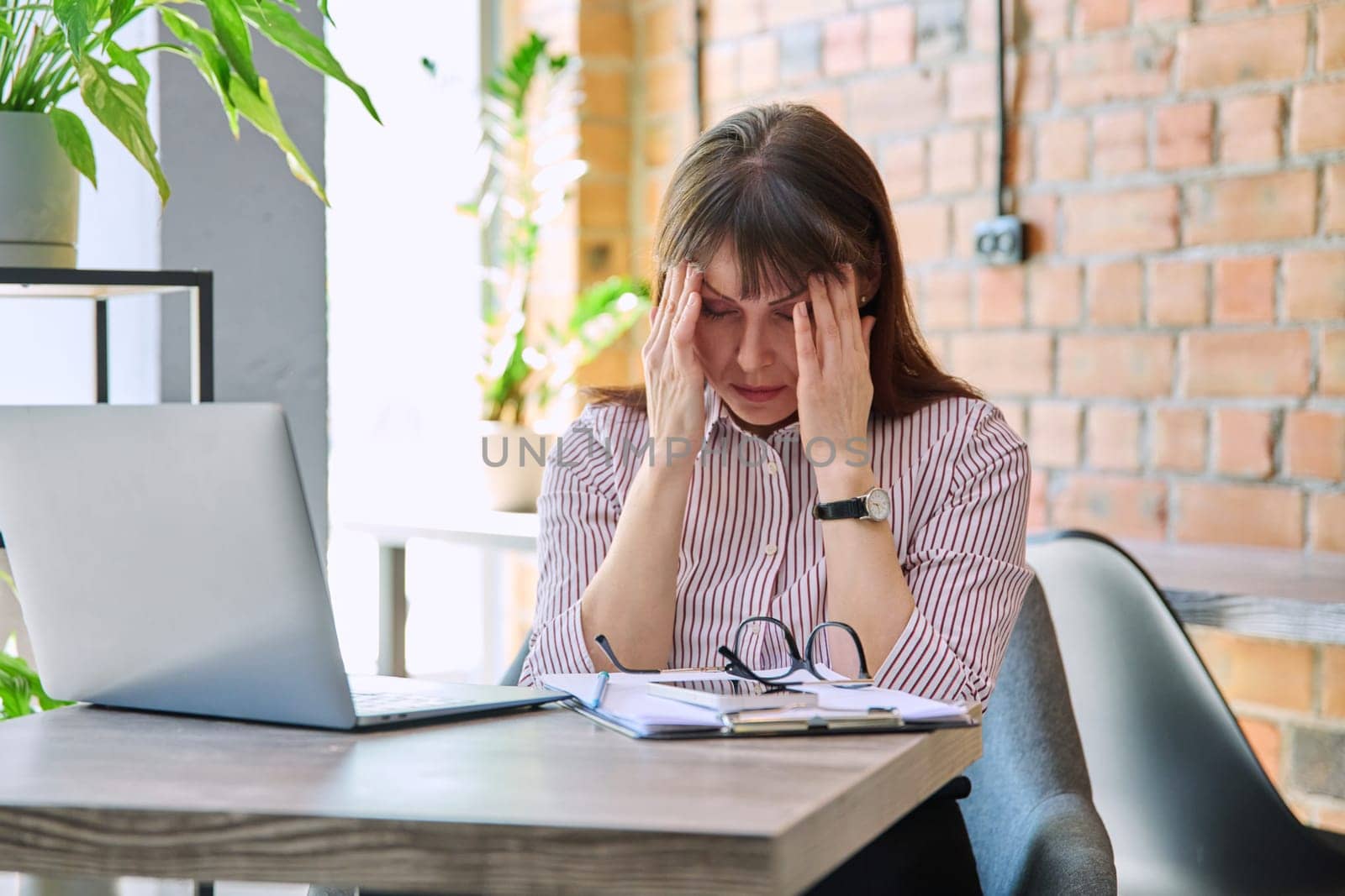 Mature tired worried tense woman at workplace experiencing stress headache. Health problems older age hormonal diseases mental difficulties migraine stressful job, depression anxiety pain injury shock