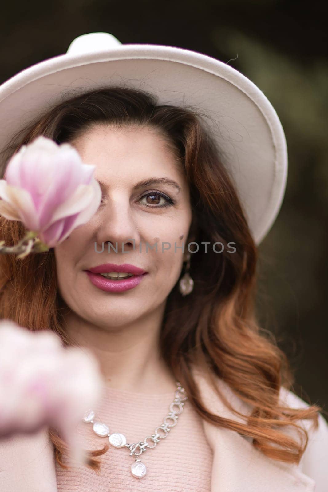 Woman holds magnolia flowers, surrounded by blossoming trees. Captured during spring, showcasing natural beauty and seasonal change