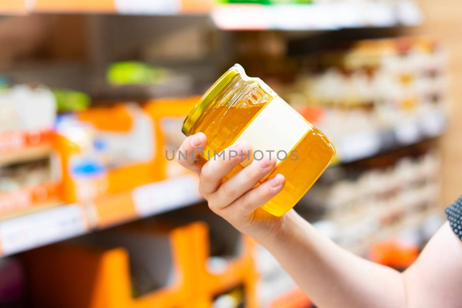 The guy in the supermarket holds a glass jar of honey by Zelenin