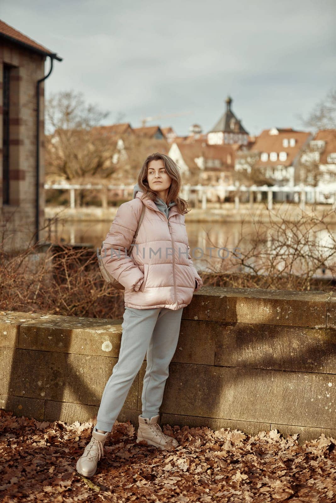 Young beautiful pretty tourist girl in warm hat and coat with backpack walking at cold autumn in Europe city enjoying her travel in Bietigheim-Bissingen, Deutschland. Outdoor portrait of young tourist woman enjoying sightseeing by Andrii_Ko