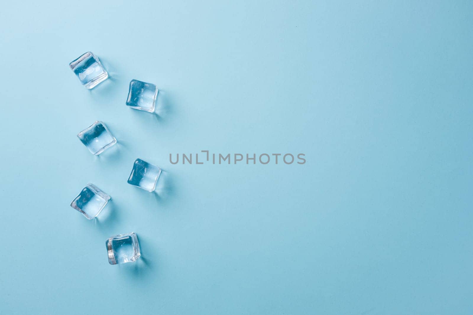 top view of ice cubes of different sizes on blue background by Sonat