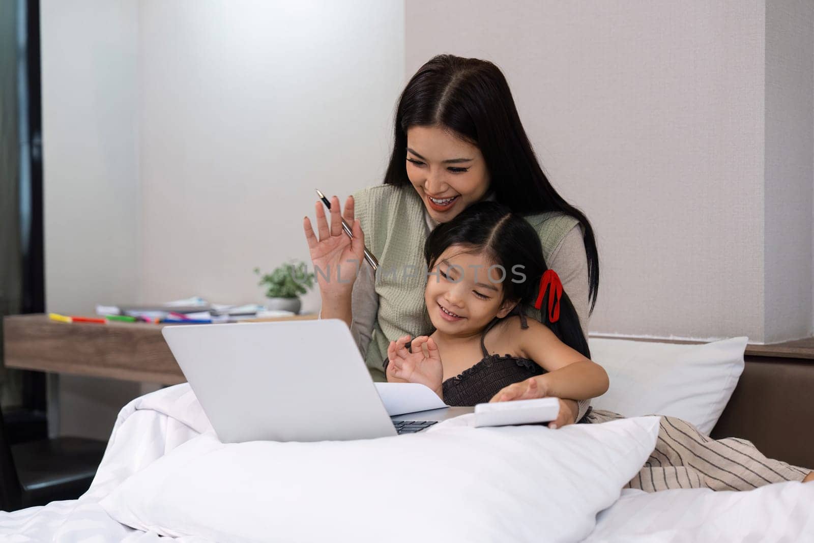 Work from home, freelance and lifestyle concept. Portrait of creative asian female sitting on bed with laptop and her take care of her kid while working by itchaznong