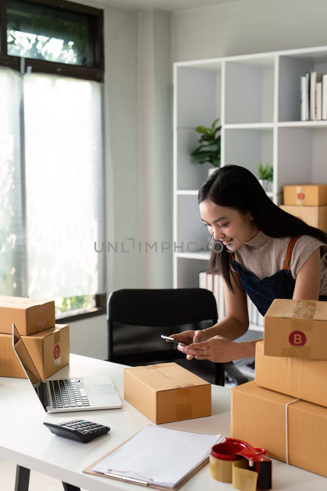 Young women taking photo product with cell telephone or smartphone digital camera for post to sell online on the Internet and preparing pack product box. Selling online ideas concept.