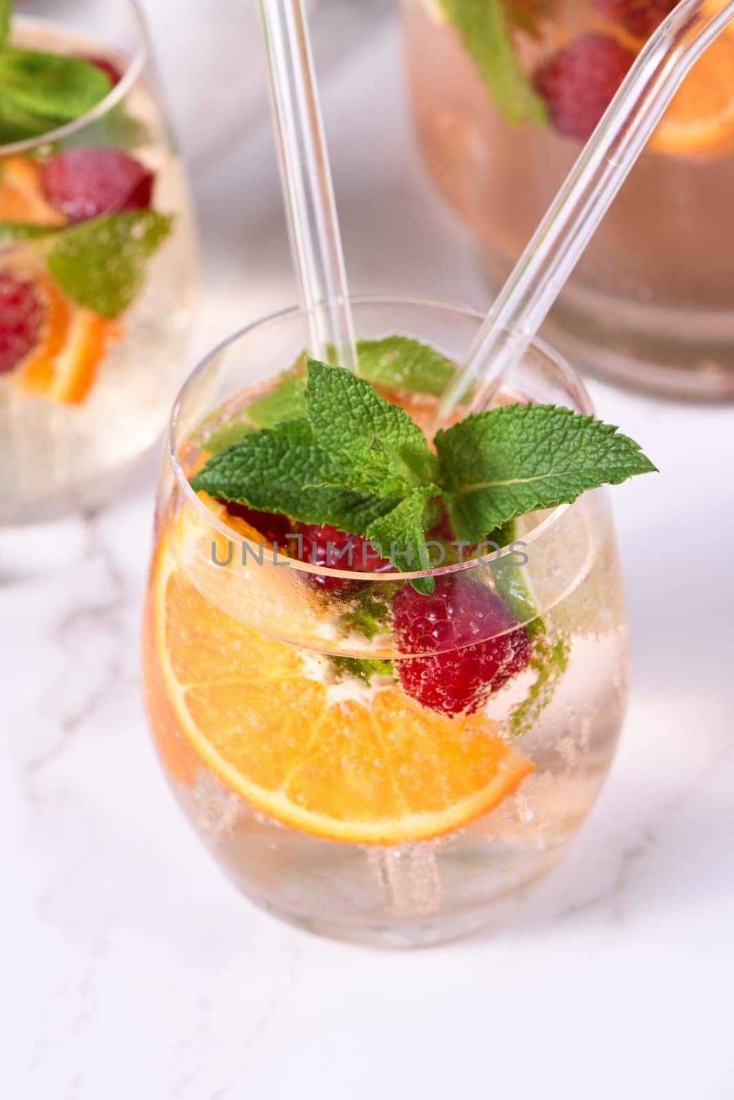 Summer Sangria cocktail or lemonade with raspberry, orange and mint. Refreshing organic non-alcoholic, Detox vitaminized healthy drink, fruit in a in a glass. Quench your thirst on a hot day.