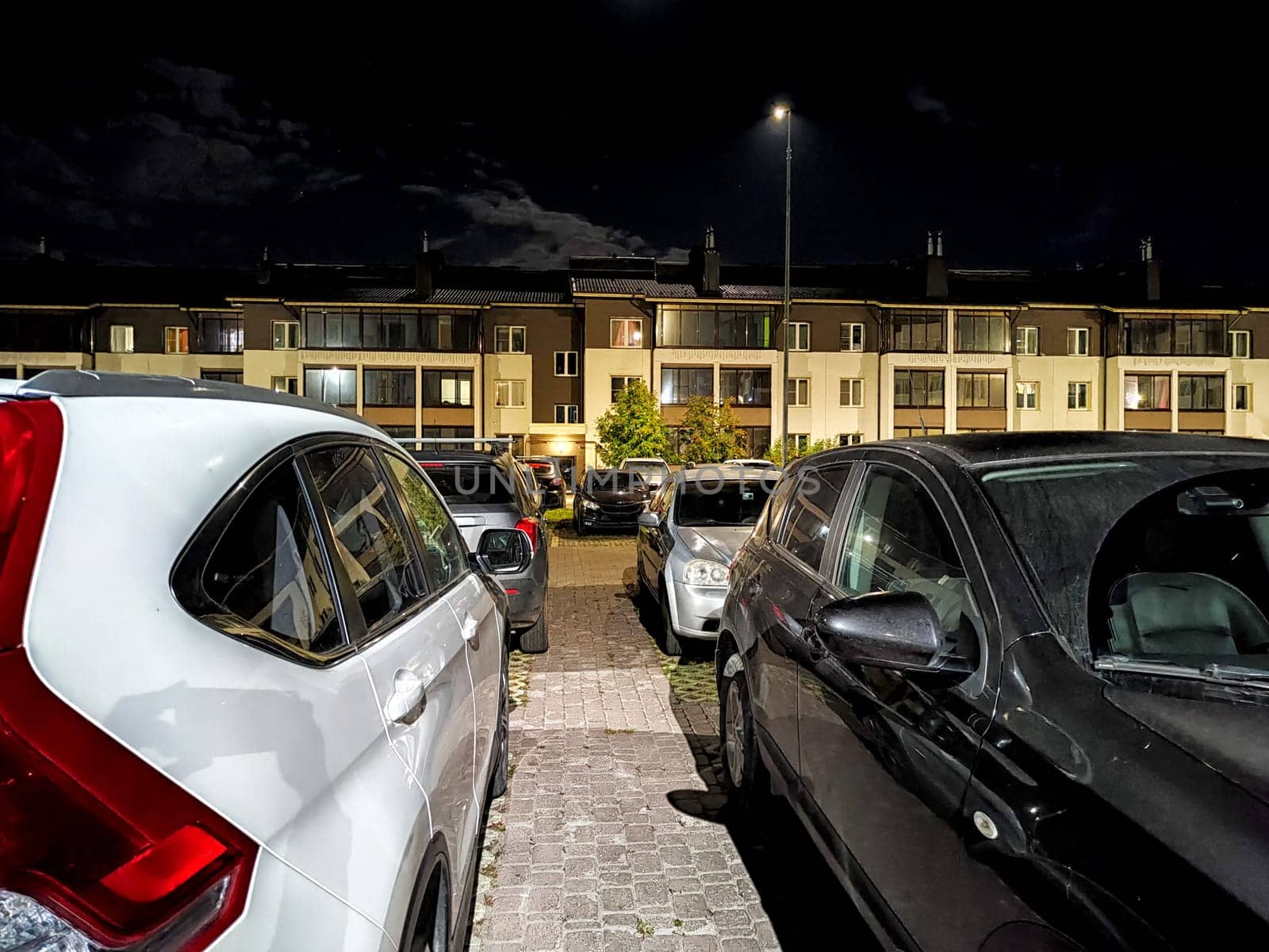 Cars parked under artificial lights against a backdrop of residential buildings at night