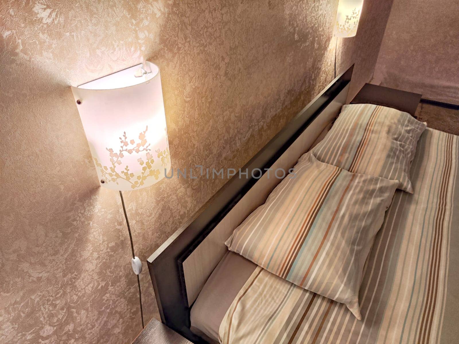 Small compact stylish bedroom in stylish soothing colors with double bed. Concept of small cozy bedroom, hotel room