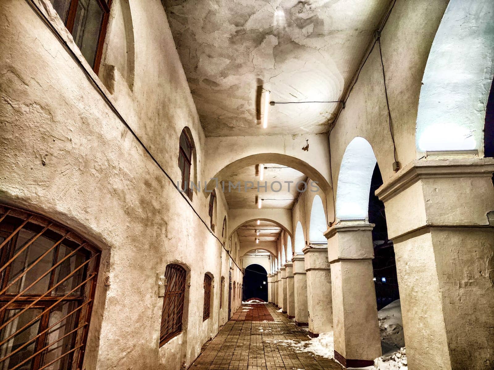 Old Ancient Colonnade Pathway at Night in dark. Dimly lit corridor with arches and age-worn columns