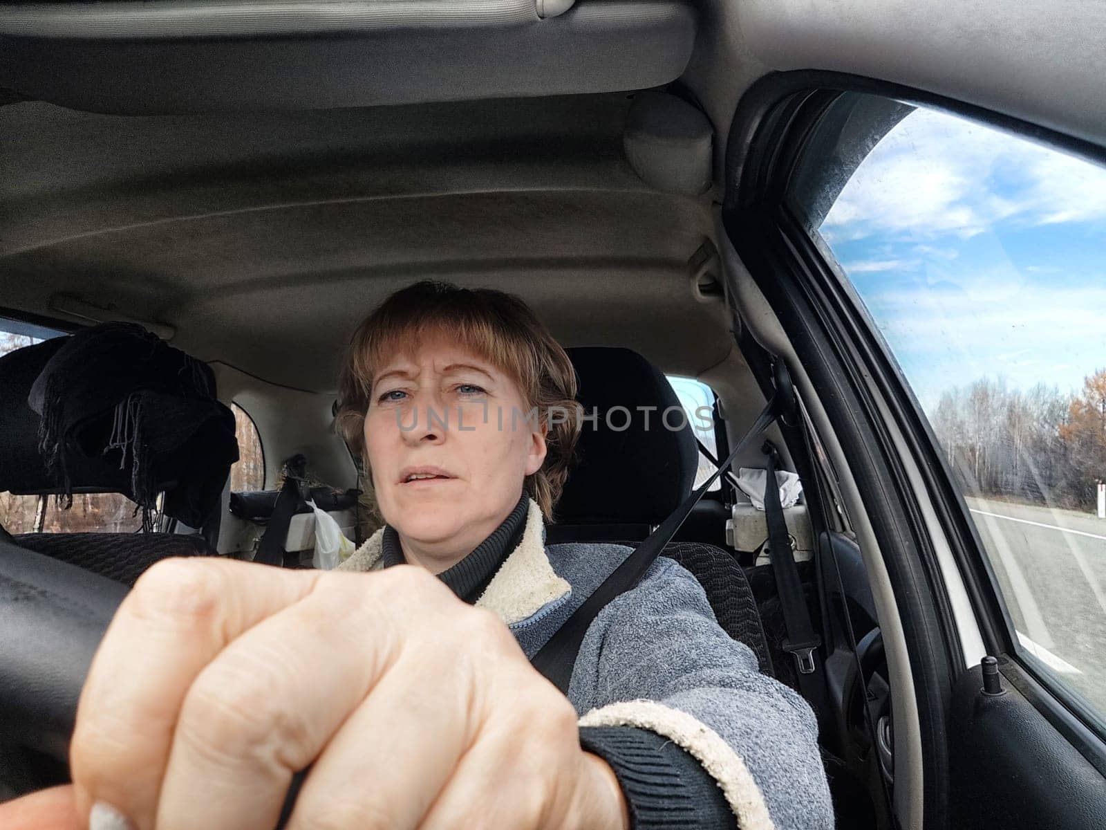 Terrified female driver a second before the accident. Scared middle-aged adult woman holds the steering wheel of car. Frightened Lady girl who is owner or rent a car for travel